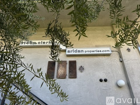 A wall with a sign that says "Aridan properties.com" and a window with a metal grate.