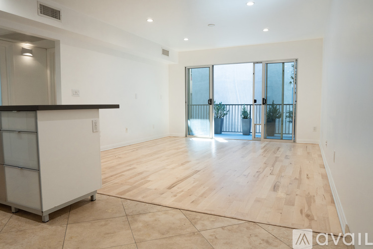 A spacious room with wooden flooring and a bar area.