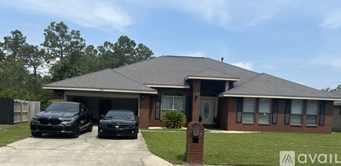 Two black cars are parked in front of a brick house.
