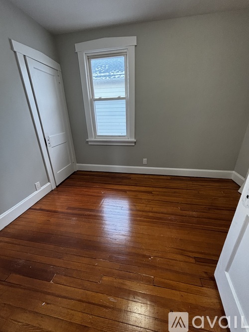 A room with wooden flooring and a window.