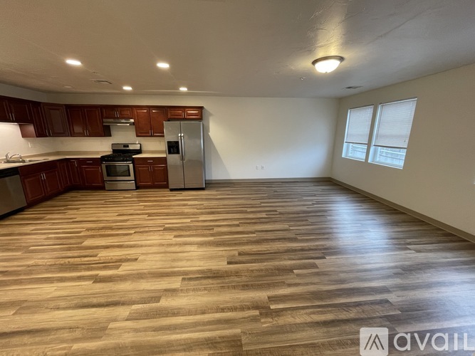 A spacious kitchen with wooden flooring and a refrigerator.