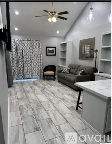 A living room with a grey couch and a ceiling fan.