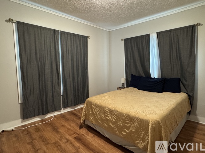 A bedroom with a bed, pillows, and curtains.