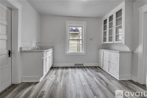 A kitchen with white cabinets and a window with blinds.