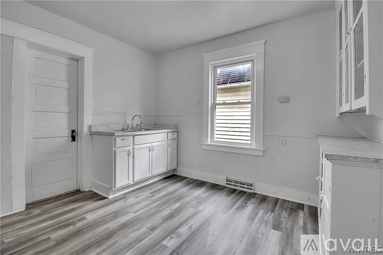 A kitchen with white cabinets and a wooden floor.