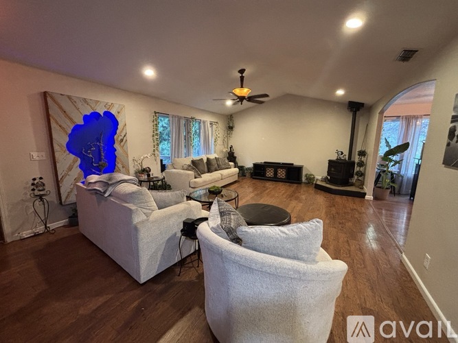 A living room with a white couch and a blue abstract painting on the wall.