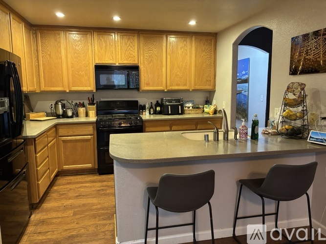 A kitchen with wooden cabinets and a white island with two chairs.