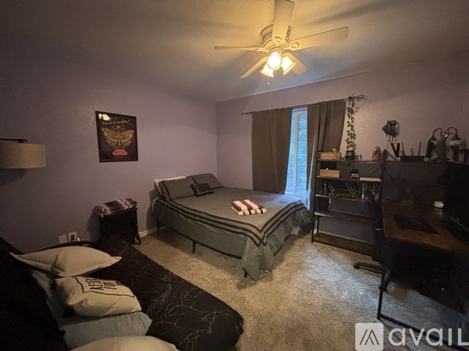 A bedroom with a bed, a ceiling fan, and a window with curtains.