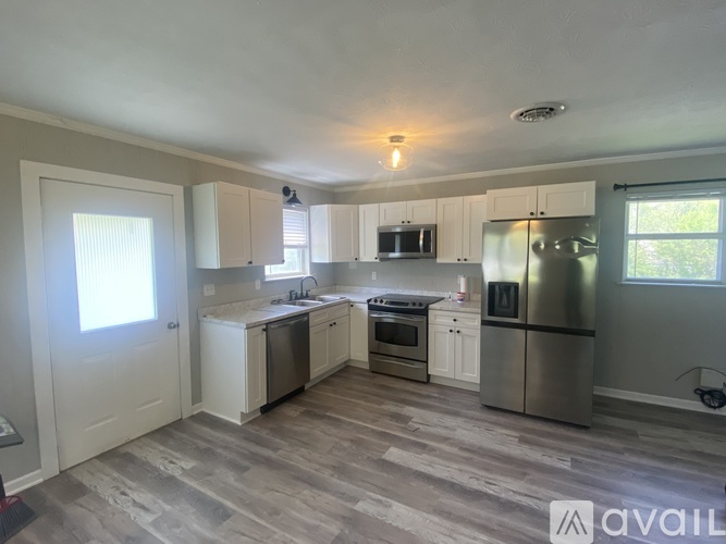 A kitchen with white cabinets and a grey floor.