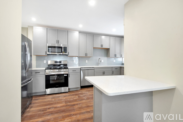 A modern kitchen with stainless steel appliances and wooden flooring.
