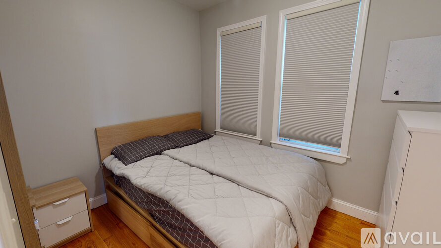 A bedroom with a bed, nightstand, and window with blinds.