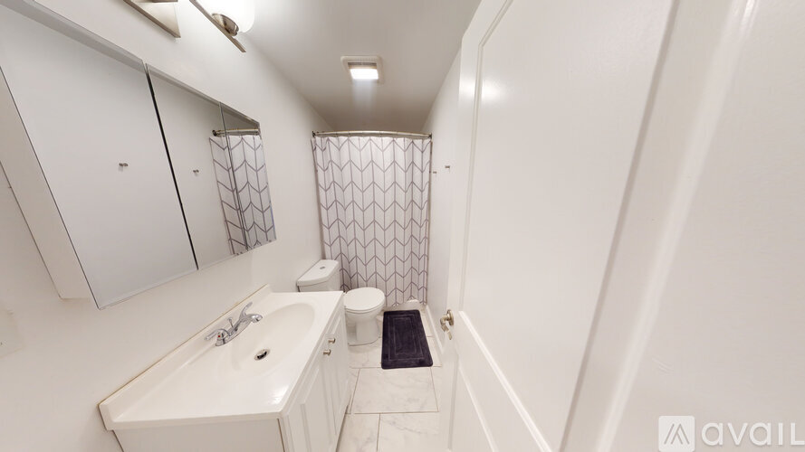 A white bathroom with a sink, toilet, and shower.