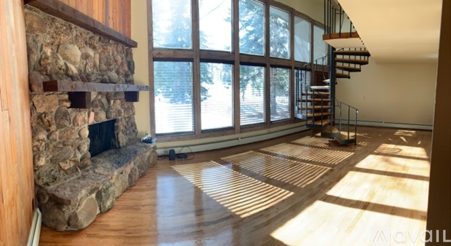 A living room with a stone fireplace and a spiral staircase.
