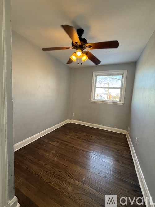 A room with a ceiling fan and wooden flooring.
