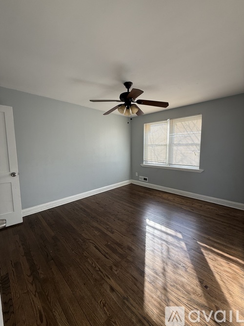 A room with a ceiling fan and wooden flooring.