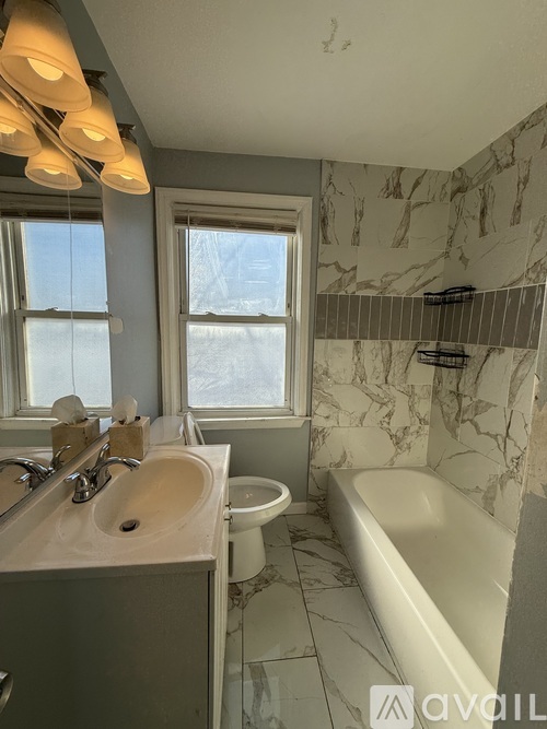 A bathroom with a marble wall and a white bathtub.