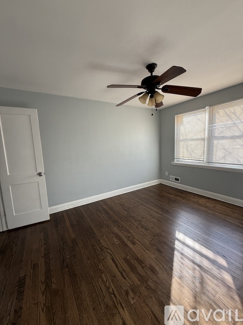 A room with a ceiling fan and wooden flooring.