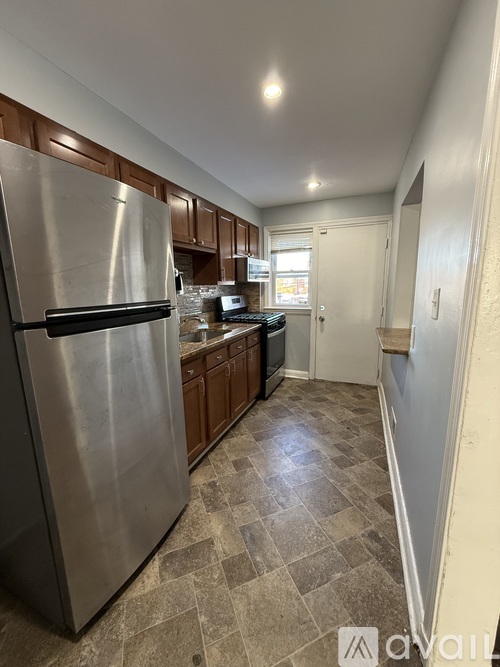 A kitchen with a refrigerator, cabinets, and a checkered floor.