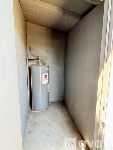 A metal container with a red label is in a narrow space between two walls.