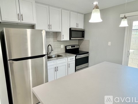 A kitchen with a stainless steel refrigerator and white cabinets.