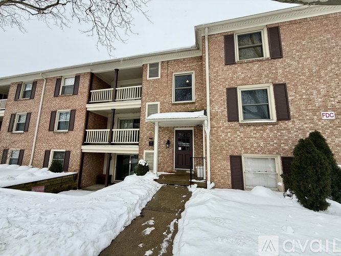 A brick apartment building with a snow covered walkway in front.