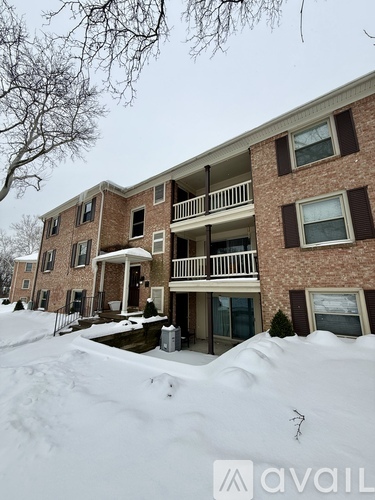 A snow-covered building with a balcony and a tree in the foreground.