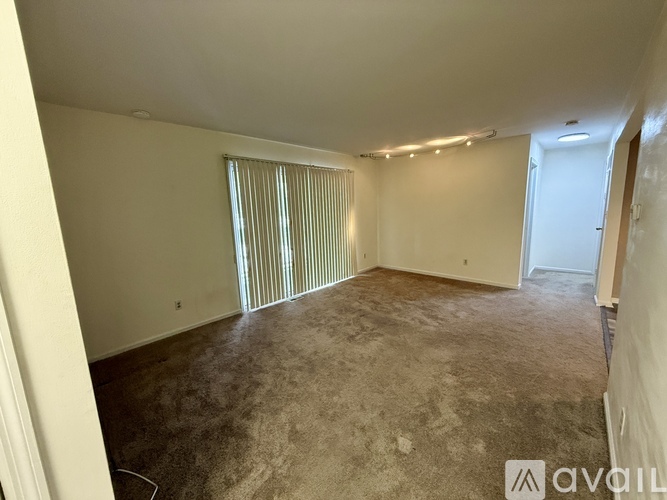 A room with a carpeted floor and a window with blinds.