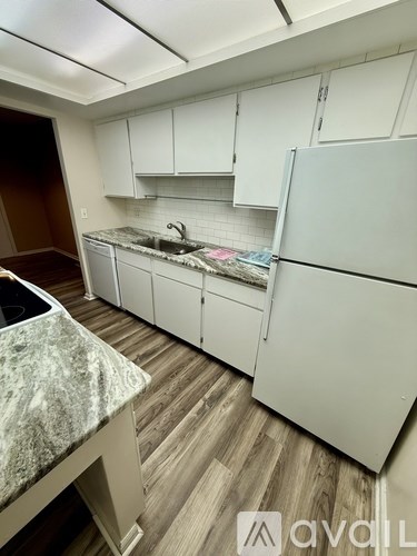 A kitchen with white cabinets and a marble countertop.