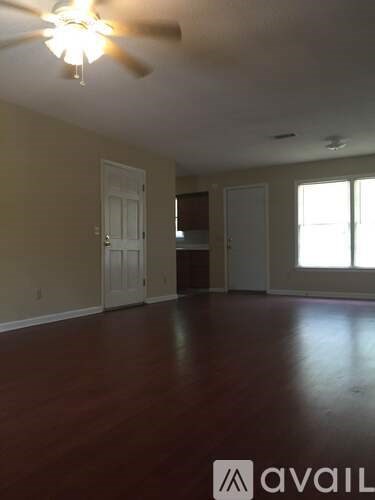 A room with a ceiling fan and wooden floors.