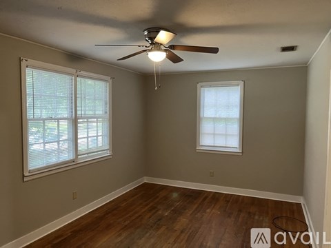 A room with a ceiling fan and two windows.