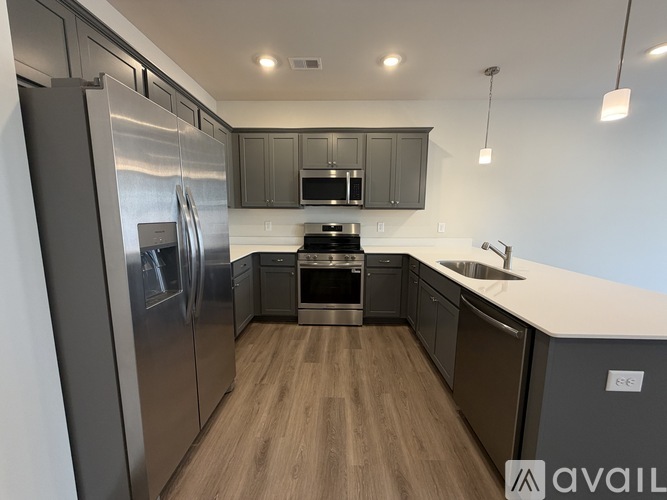 A modern kitchen with stainless steel appliances and wooden flooring.