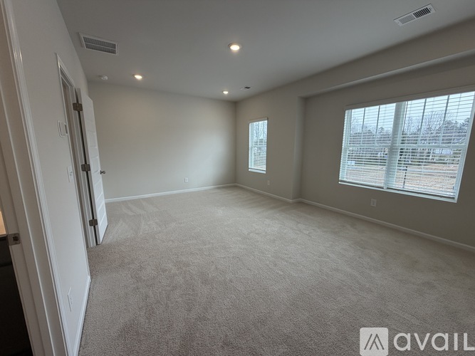 A spacious room with carpeted floor and a large window with blinds.