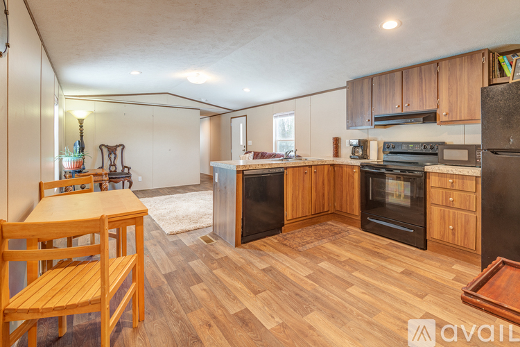 A kitchen with wooden floors and black appliances.