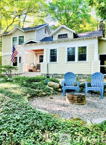 A yellow house with a porch and two blue chairs.