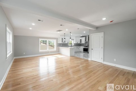 A spacious kitchen and living room with wooden floors and white walls.