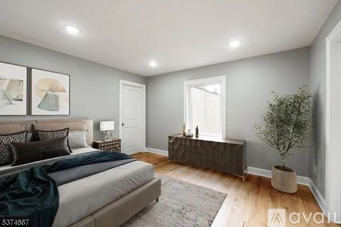 A bedroom with a bed, nightstand, and a plant.