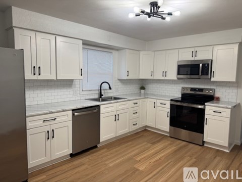 A kitchen with white cabinets and wooden floors.