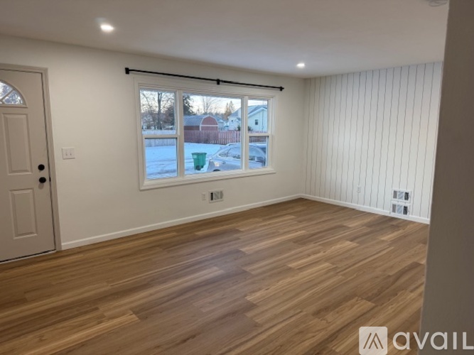 A room with wooden flooring and a window overlooking a snowy landscape.