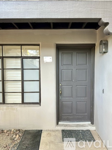 A grey door is on the right of a window with white shutters.
