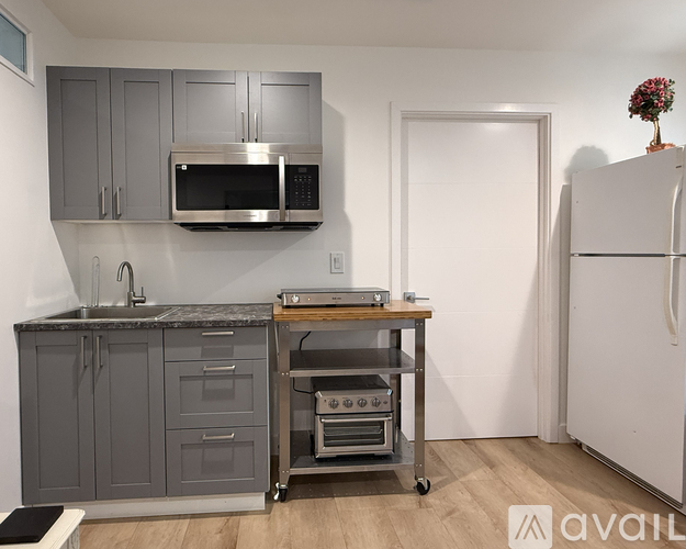 A kitchen with a white refrigerator, grey cabinets, and a microwave above the counter.