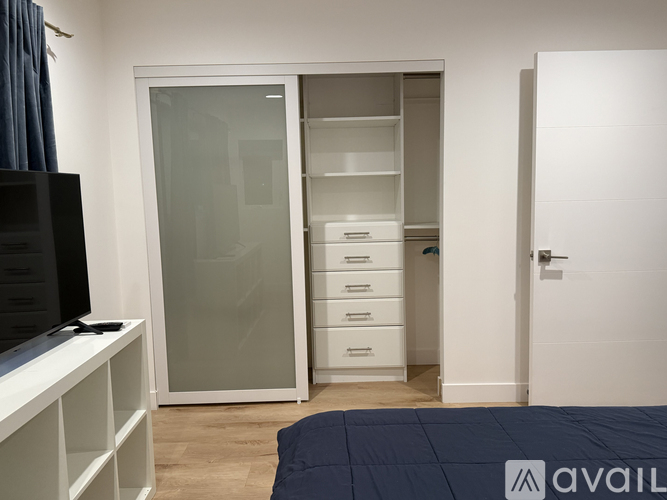 A bedroom with a large wardrobe and a television.