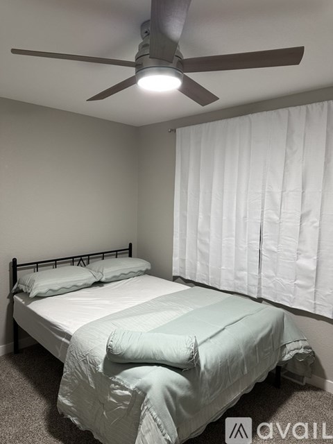 A bedroom with a bed, pillows, and a ceiling fan.