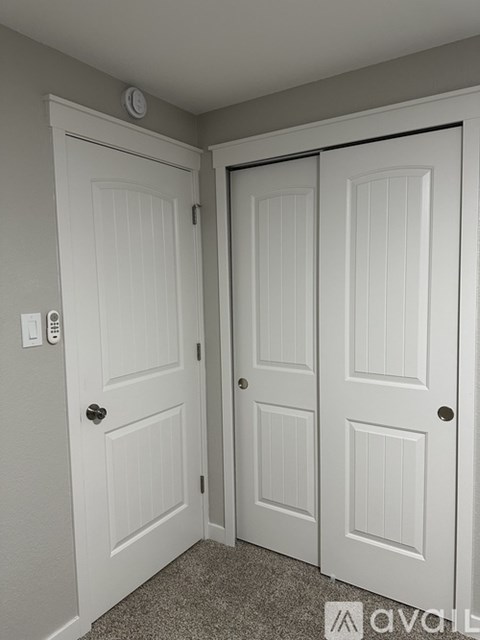 A white door with a black handle and a round knob on the wall.