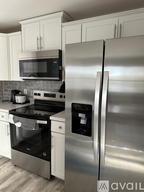 A kitchen with a stainless steel refrigerator and a black microwave above the stove.
