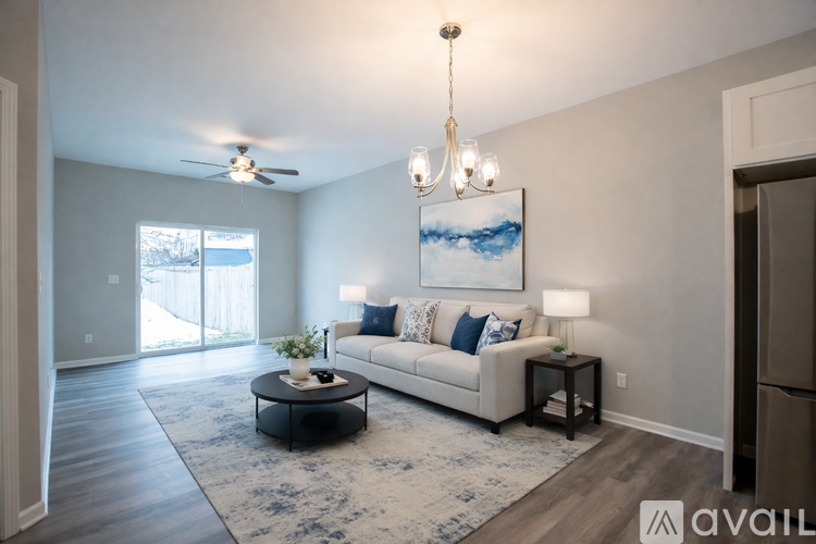 A living room with a white couch, a painting on the wall, and a chandelier hanging from the ceiling.