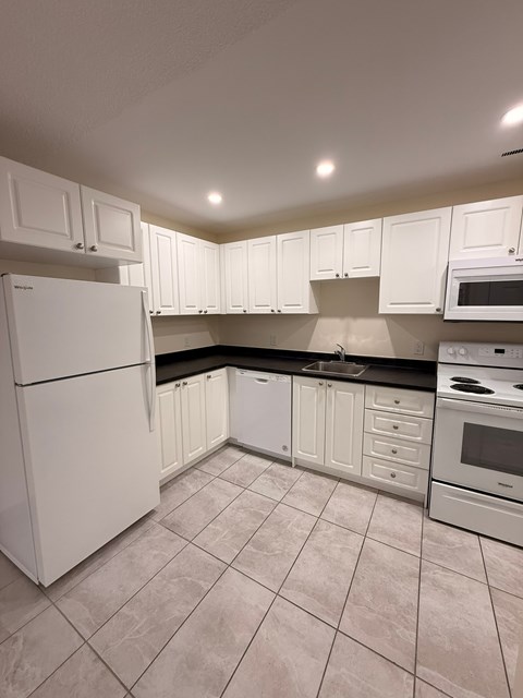 A kitchen with white cabinets and appliances.