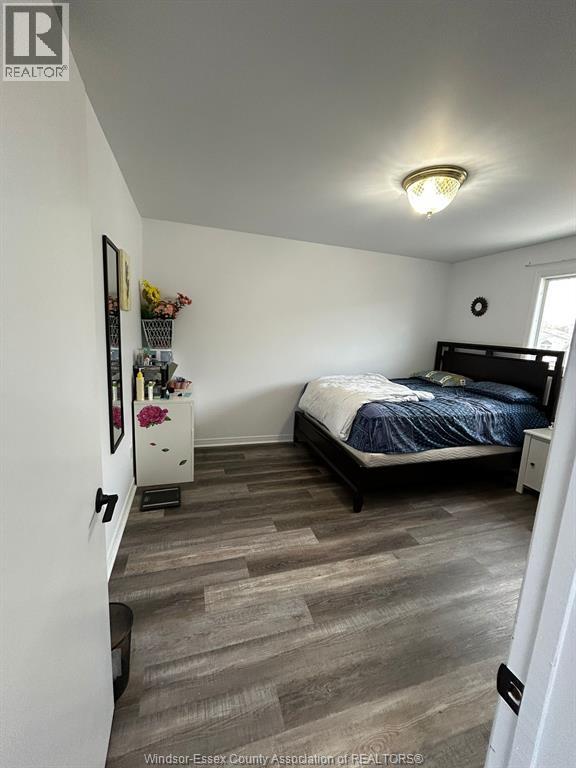 A bedroom with a bed, nightstand, and a dresser with a mirror.