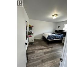 A bedroom with a bed, nightstand, and a dresser with a mirror.