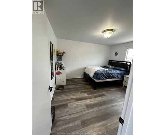A bedroom with a bed, nightstand, and a dresser with a mirror.