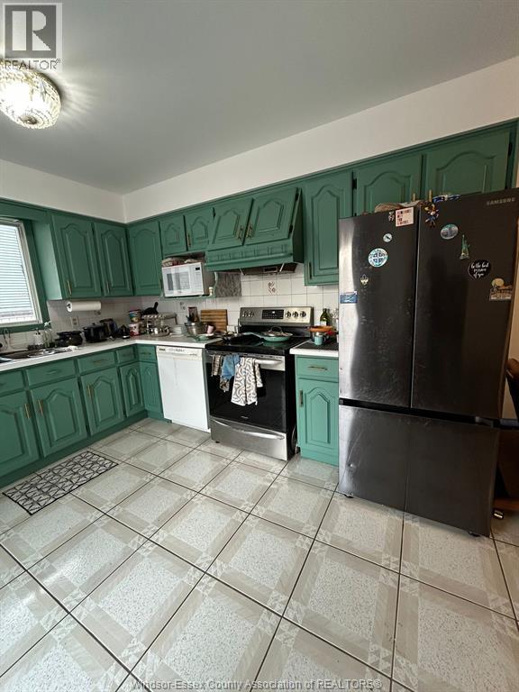 A kitchen with green cabinets and a black fridge.